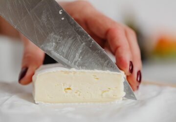 Hands of a Woman Slicing White Cheese