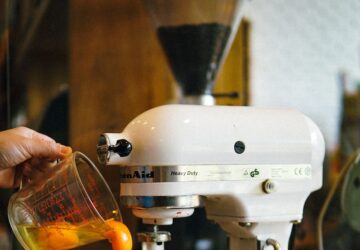 person pouring egg yolks on white stand mixer
