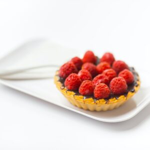 photo of chocolate cupcake with berry toppings on white ceramic plate