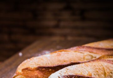 Close-up Photo of Three Baguettes on Brown Wooden Surface With White Powder