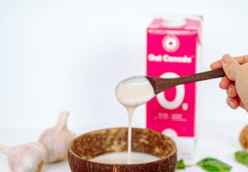 person holding stainless steel spoon and brown ceramic bowl
