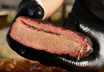 person holding raw meat during daytime