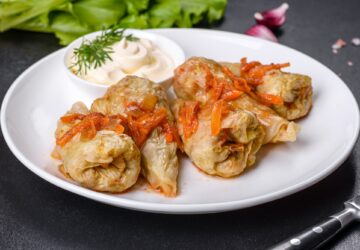Cabbage rolls stuffed with ground beef and rice served on a white plate