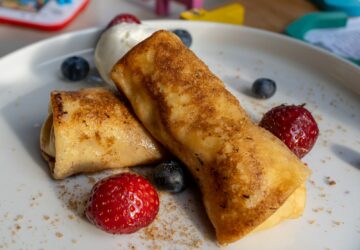 Closeup shot of cheese blintz with strawberries and blueberries on a white plate