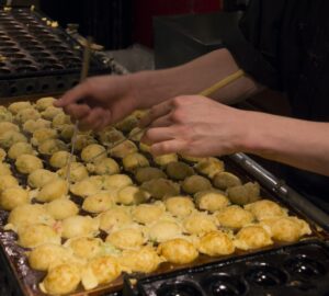 Cook rolling takoyaki in a traditional Japanese restaurant in Osaka (Japan)