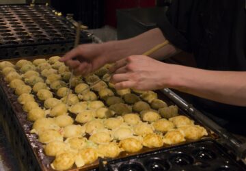 Cook rolling takoyaki in a traditional Japanese restaurant in Osaka (Japan)