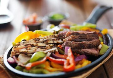 steak and chicken fajitas close up in cast iron fajita skillet