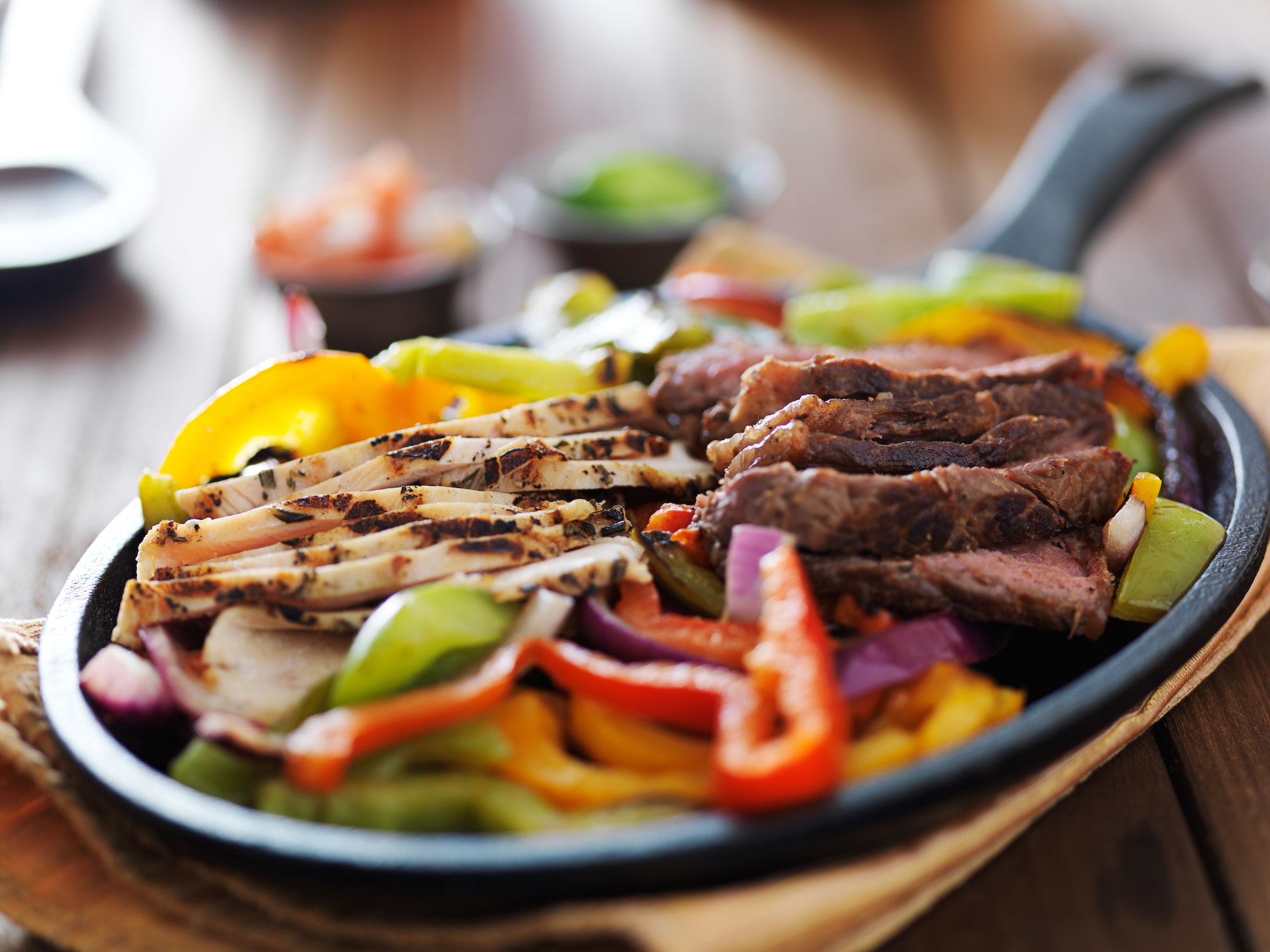 steak and chicken fajitas close up in cast iron fajita skillet