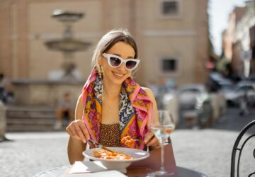 Woman eating italian pasta at restaurant on the street in Rome