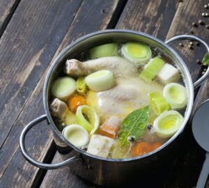 Cooking pot with raw corn-fed chicken, onion, herbs and greens