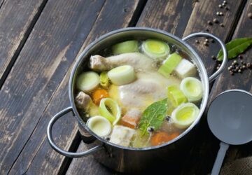 Cooking pot with raw corn-fed chicken, onion, herbs and greens