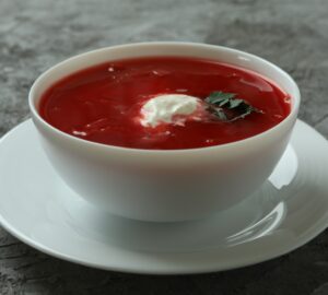Bowl of tasty borscht on gray background