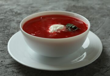 Bowl of tasty borscht on gray background
